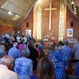 inside of sanctuary with alter cross and congregation standing