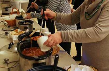 ladies helping themselves to soup from several crock pots