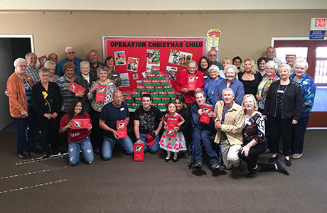 30 members of our congregation standing with the large stack of christmas shoeboxes to send overseas